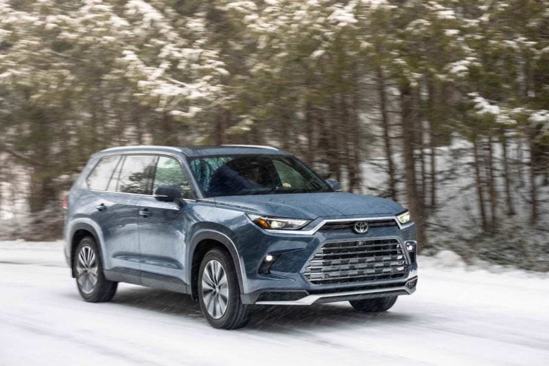 A 2024 Grand Highlander is seen on a snowy road in the forest.