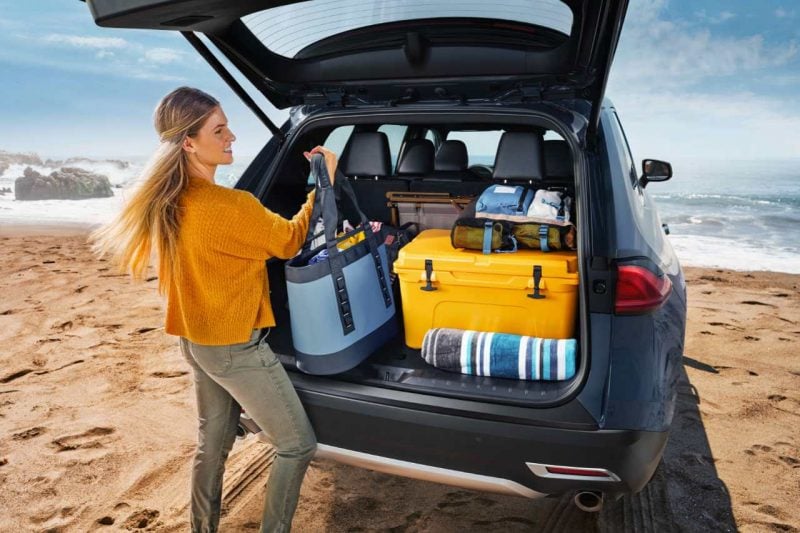 A woman is placing baggage into the cargo space of a 2024 Grand Highlander vehicle.