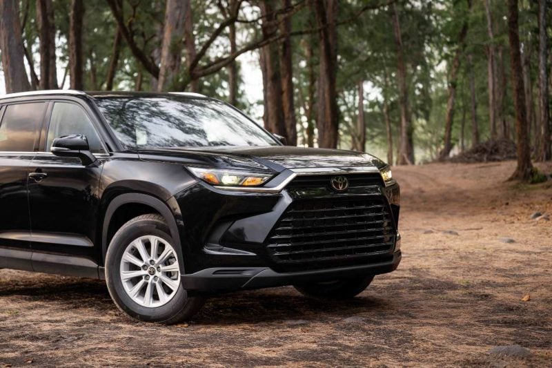 A 2024 Grand Highlander vehicle is seen parked on a dirt road in the forest.