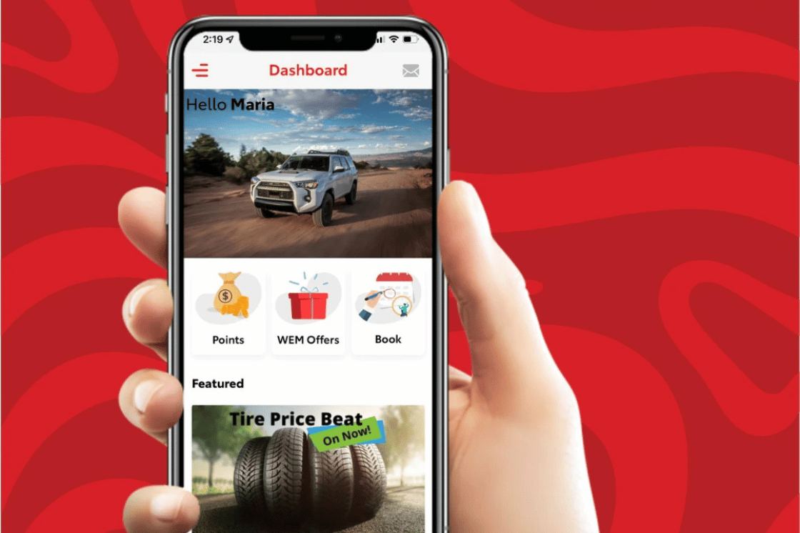 A phone showcasing the West Edmonton Mall Toyota app is held by a hand.