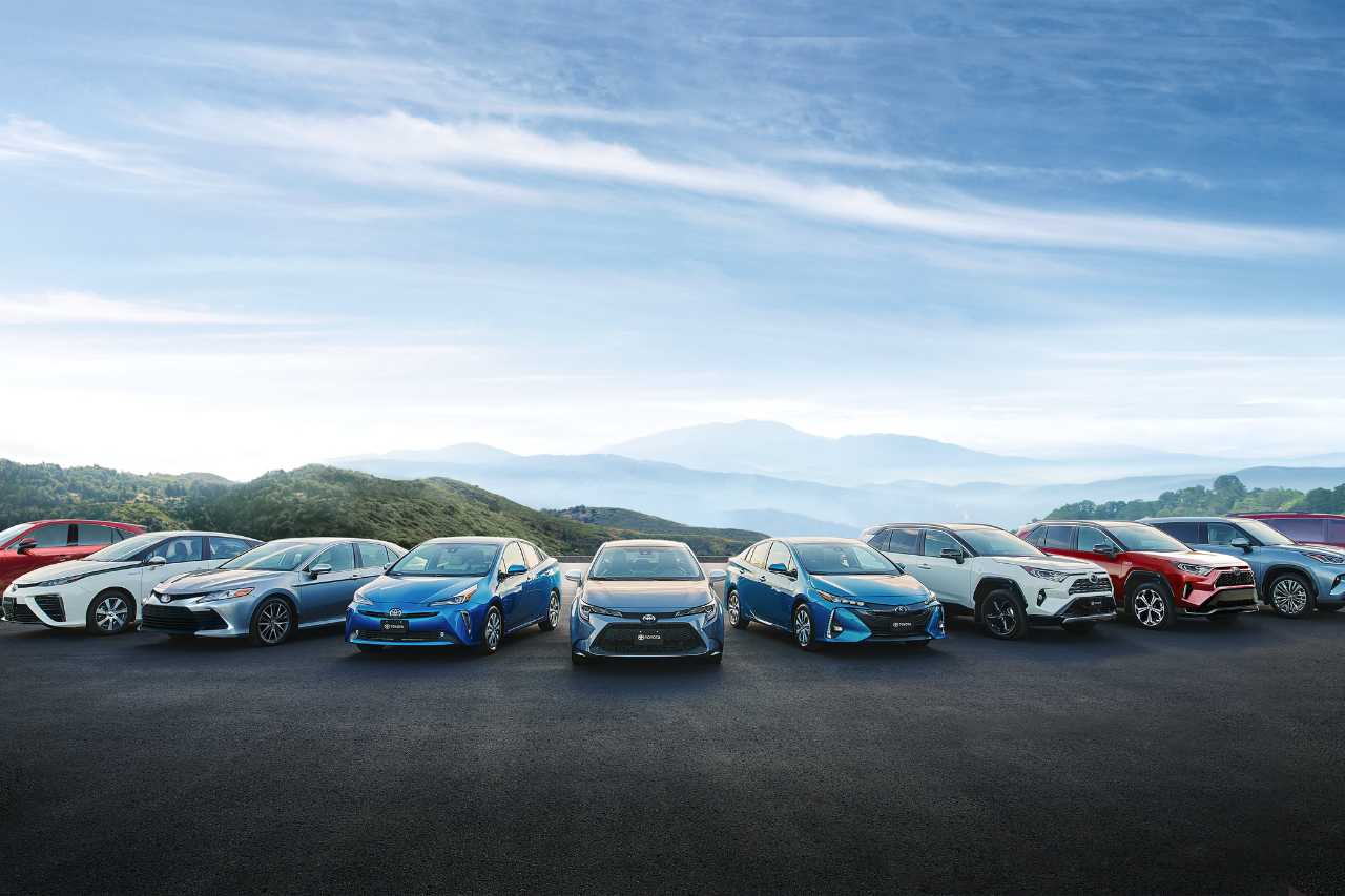 A lineup of Toyota electric and hybrid vehicles under a blue sky.