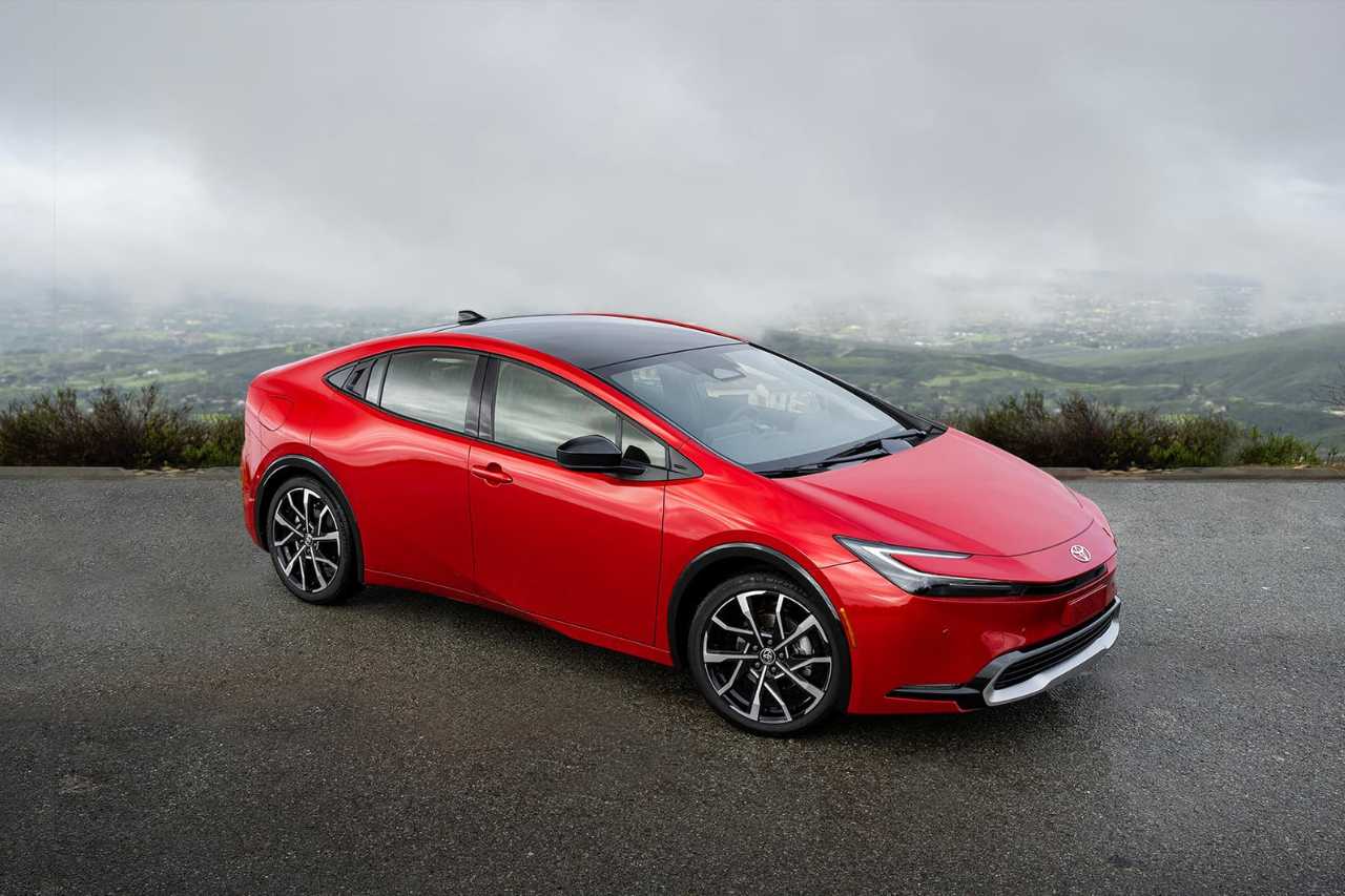 A red Prius Prime electric vehicle is parked on a road on a cloudy, foggy day.