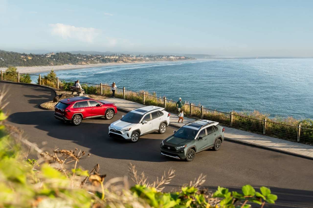 Three of the 2024 Toyota RAV4 SUVs in varying colours are parked next to a beach ocean view.