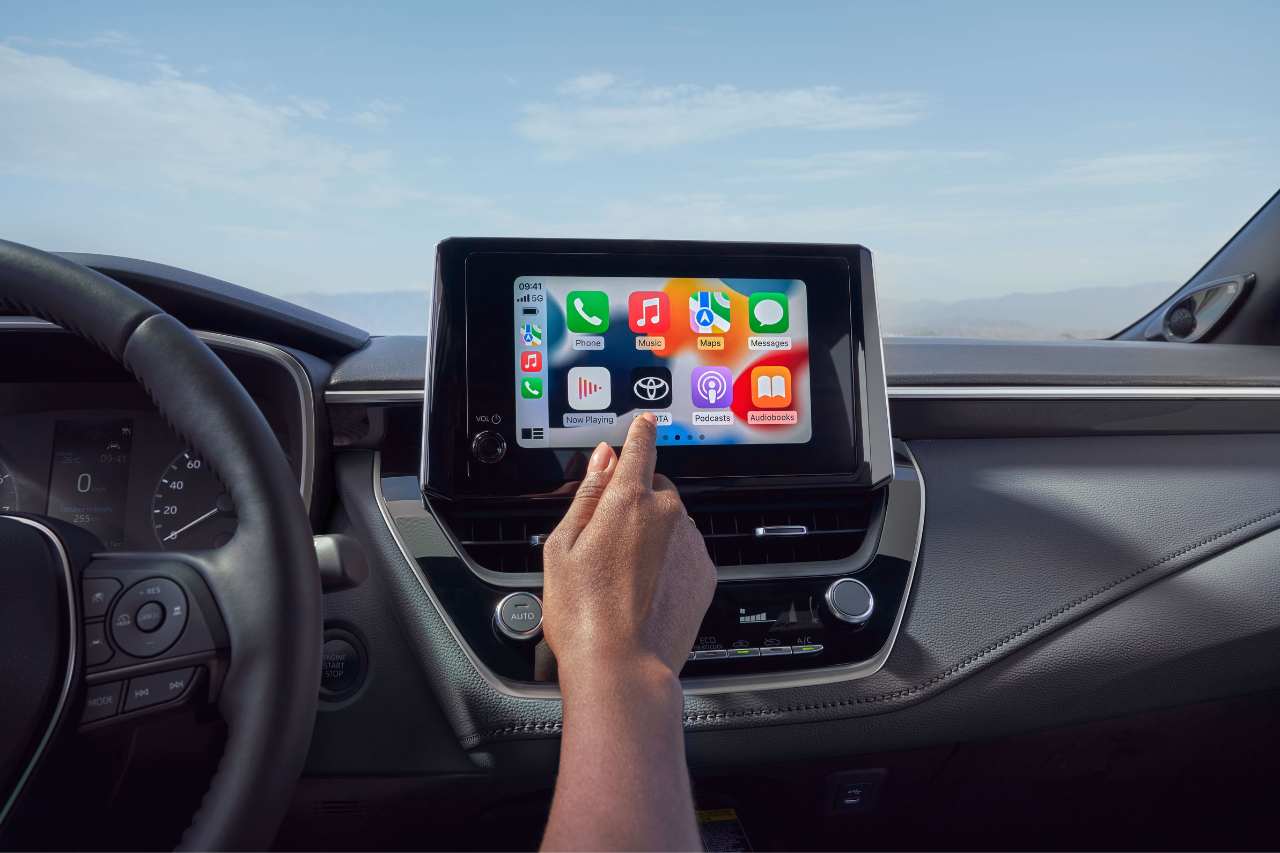 An African American driver reaches for the Toyota Multimedia screen in the 2025 Toyota Corolla Hatchback cockpit.