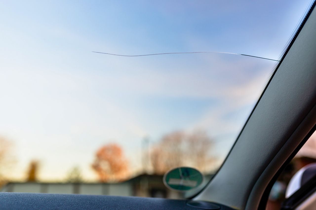 A windshield with a crack running from the side of the window towards the middle of the window.