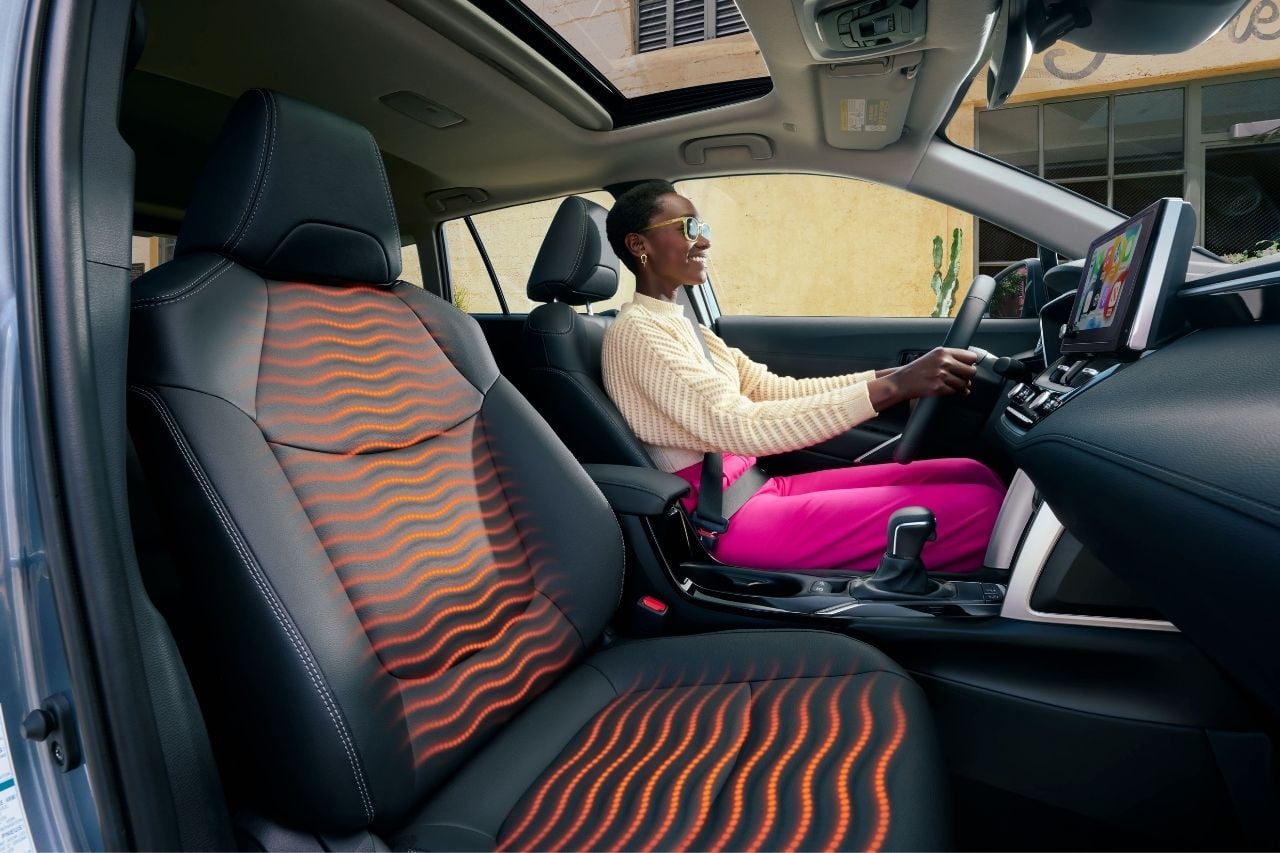 An African-American woman sits in the front seats of an SUV and enjoys heated seats.