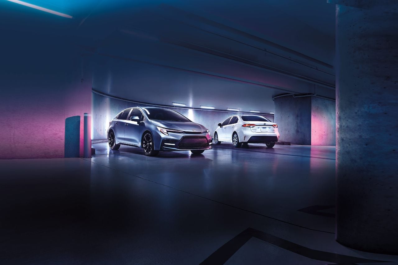 Two hybrid Corolla vehicles are parked in a futuristic parking garage, highlighting their new car shine.