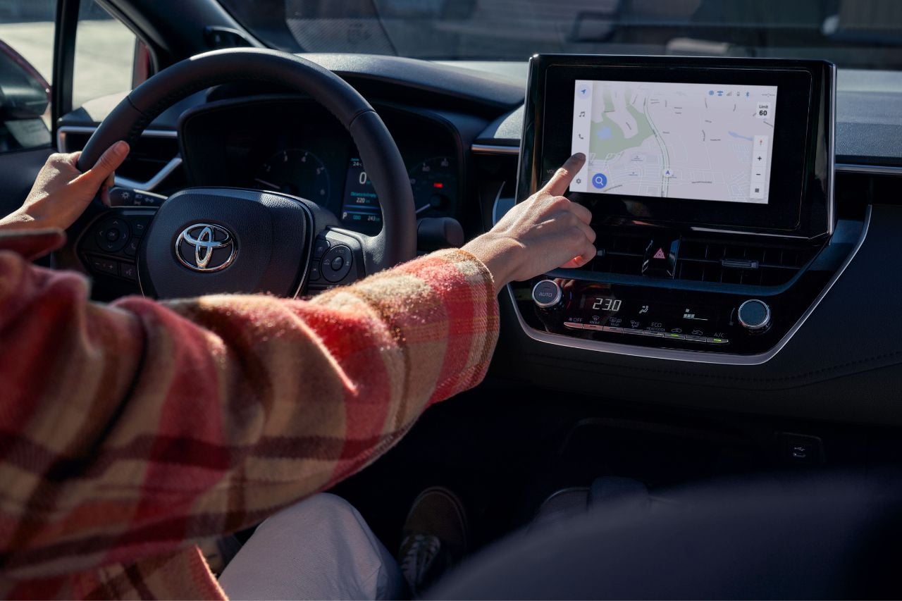 A young white woman uses the touchscreen display in a brand new 2025 Toyota Corolla sedan.