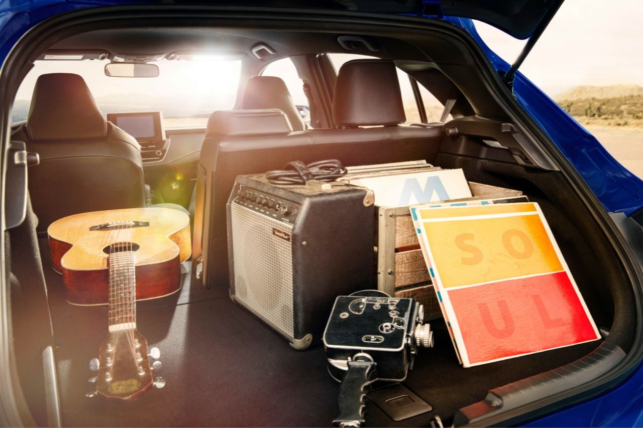 A guitar, sound equipment and some luggage are packed into the open hatch of the Corolla hatchback.