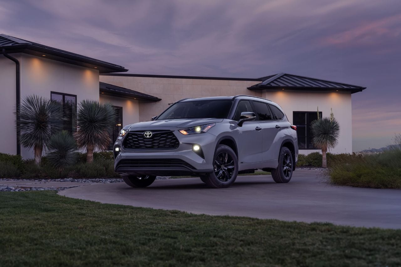 A moody white SUV with dark black trim is parked outside a modern home at dusk, showcasing its features.