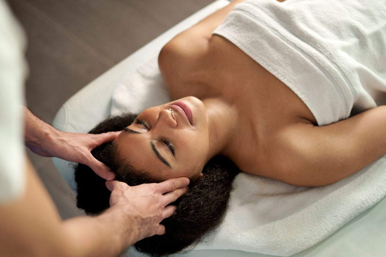 A woman has her head massaged in a relaxing massage and spa treatment.