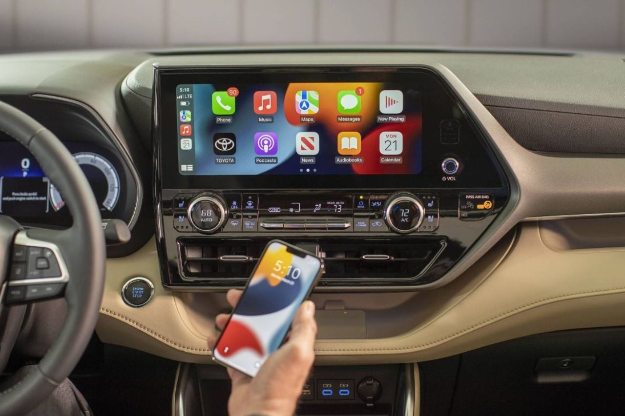 A person holds an iPhone in their Toyota vehicle. They are attempting to use Wireless Apple CarPlay.