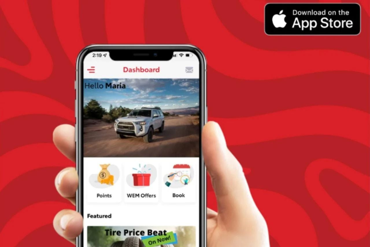 A person is holding a phone screen, showcasing the WEM Toyota App. There is a bold red pattern background behind the hand.