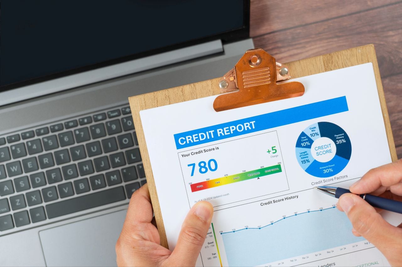 A person evaluates their credit score, printed out on a pad of paper on a clipboard.