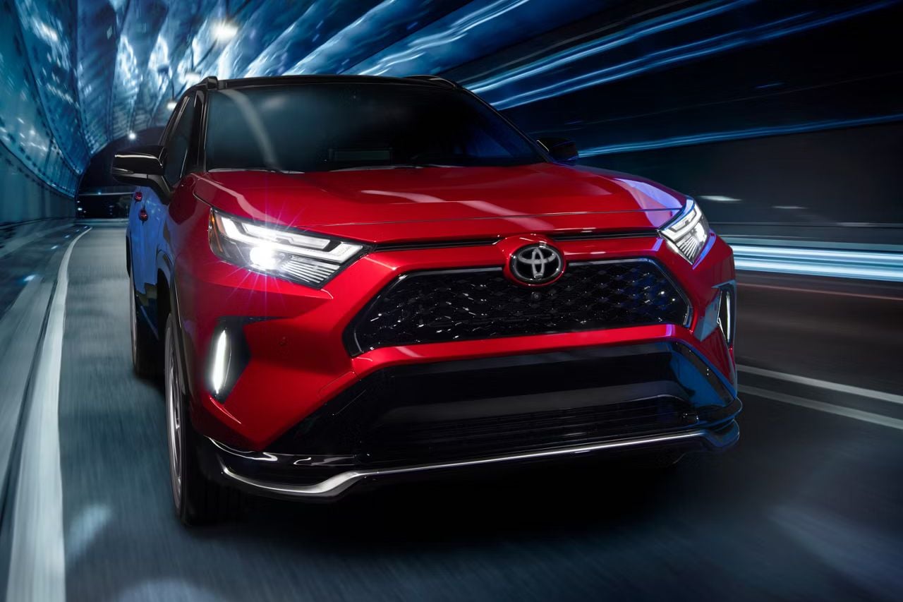 A red RAV4 SUV drives down an underground tunnel road with blurry lights zipping past.