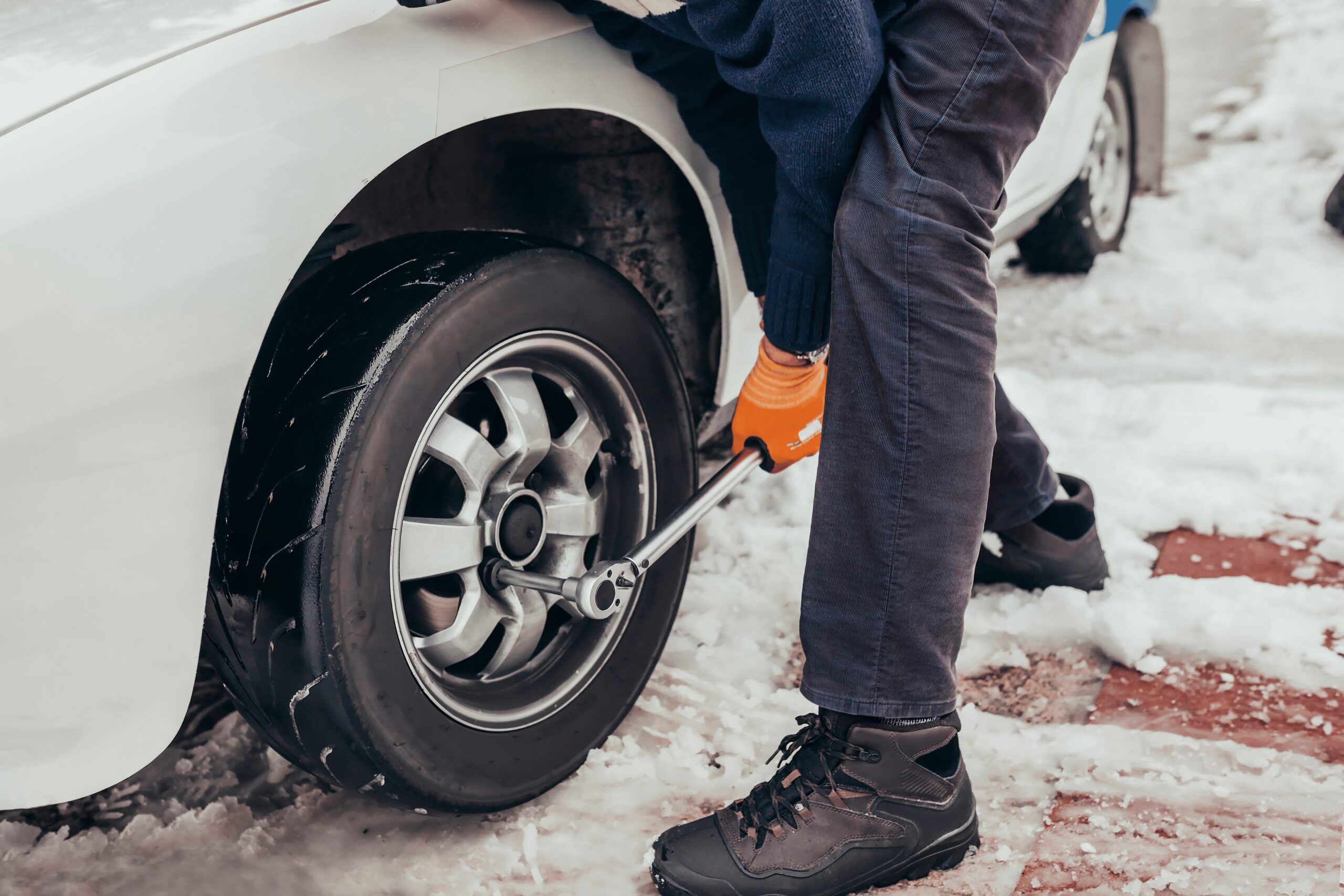 Mechanic changing car wheel on a classic car during winter