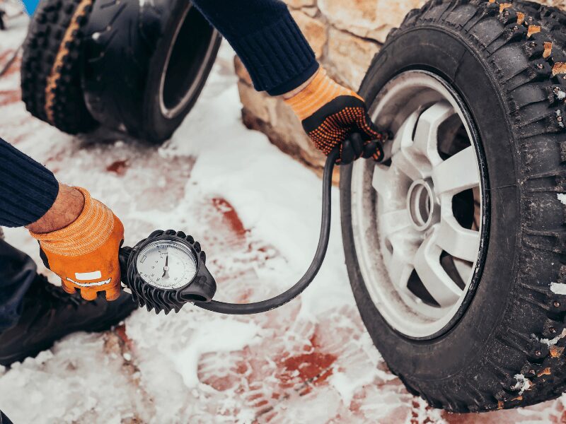 mechanic inflates wheel tire on snow road