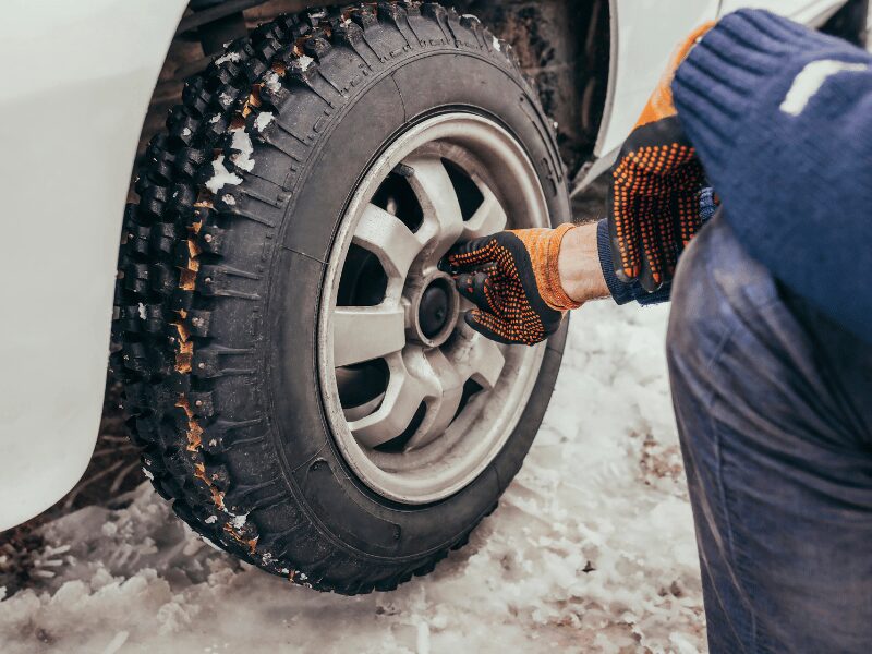 mechanic putting screw on a tire in winter