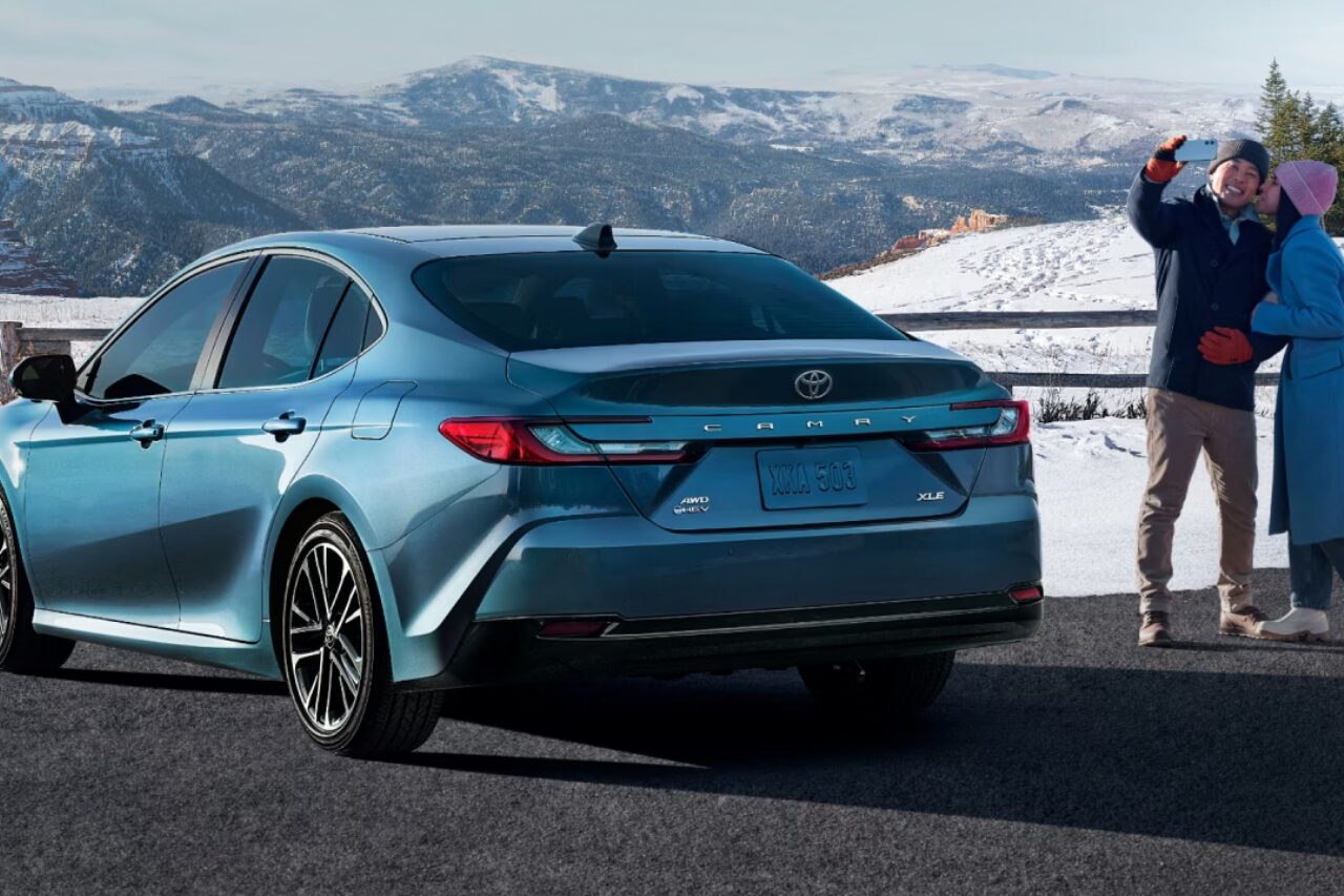 Toyota Camry AWD parked at scenic mountain overlook in winter with couple taking a photo