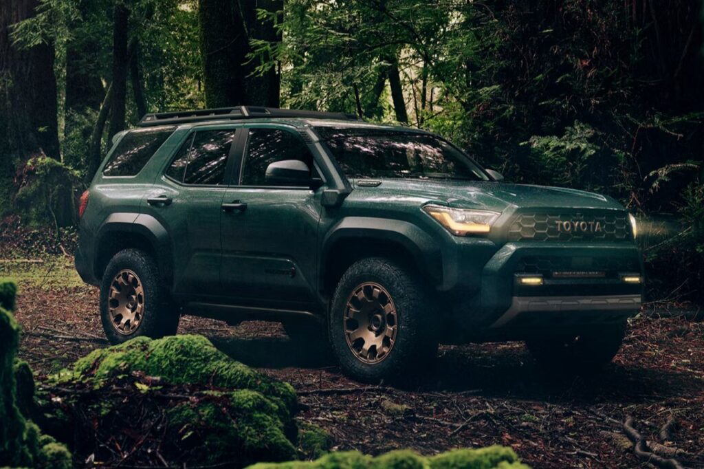 The Best Toyotas for Dads-3 A dark green Toyota 4Runner is parked in the middle of a dense forest on a camping trip.