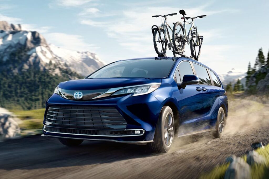 The Best Toyotas for Dads-5 A blue Toyota minivan drives down a dirt road with a bike rack mounted on top.