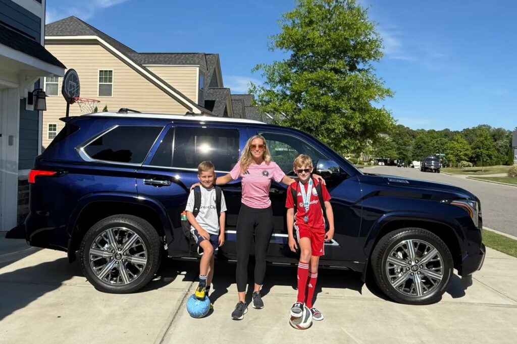 A mom stands in front of her Toyota Sequoia SUV with her two sons.