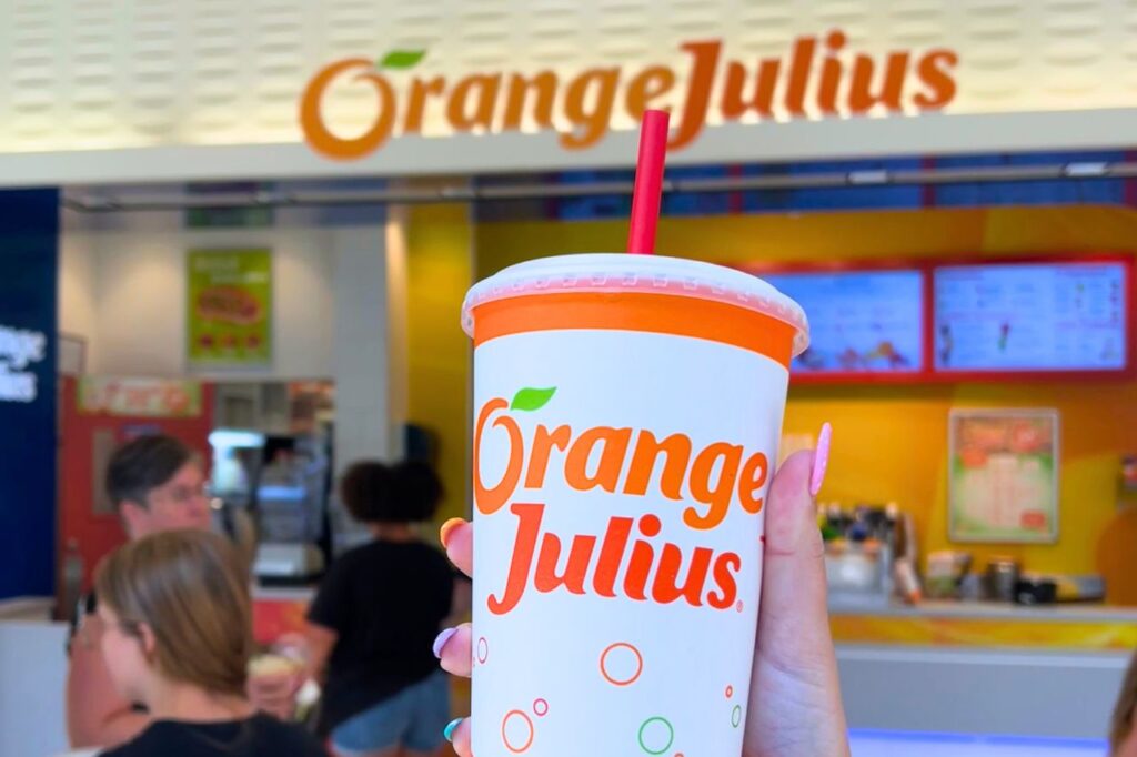 Back-to-School Shopping at West Edmonton Mall-1 A woman holds up an Orange Julius smoothie cup in front of the Orane Julius location in West Edmonton Mall.