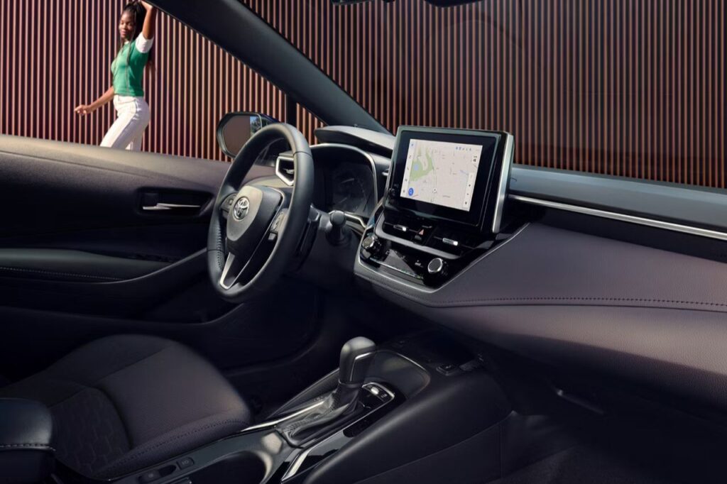 The 2027 Toyota Corolla Hatchback Is Here -1 An interior view of the cabin of a 2027 Corolla Hatchback. There are black seats, a digital screen, and a steering wheel.