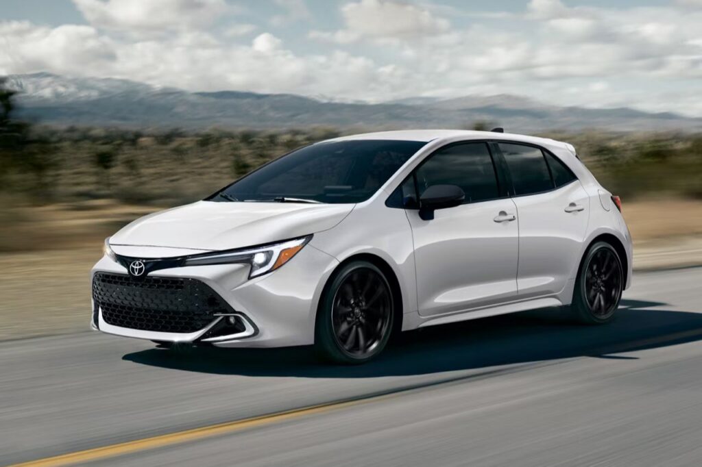The 2027 Toyota Corolla Hatchback Is Here -3 A white Toyota Corolla Hatchback speeds down a highway on a sunny afternoon.